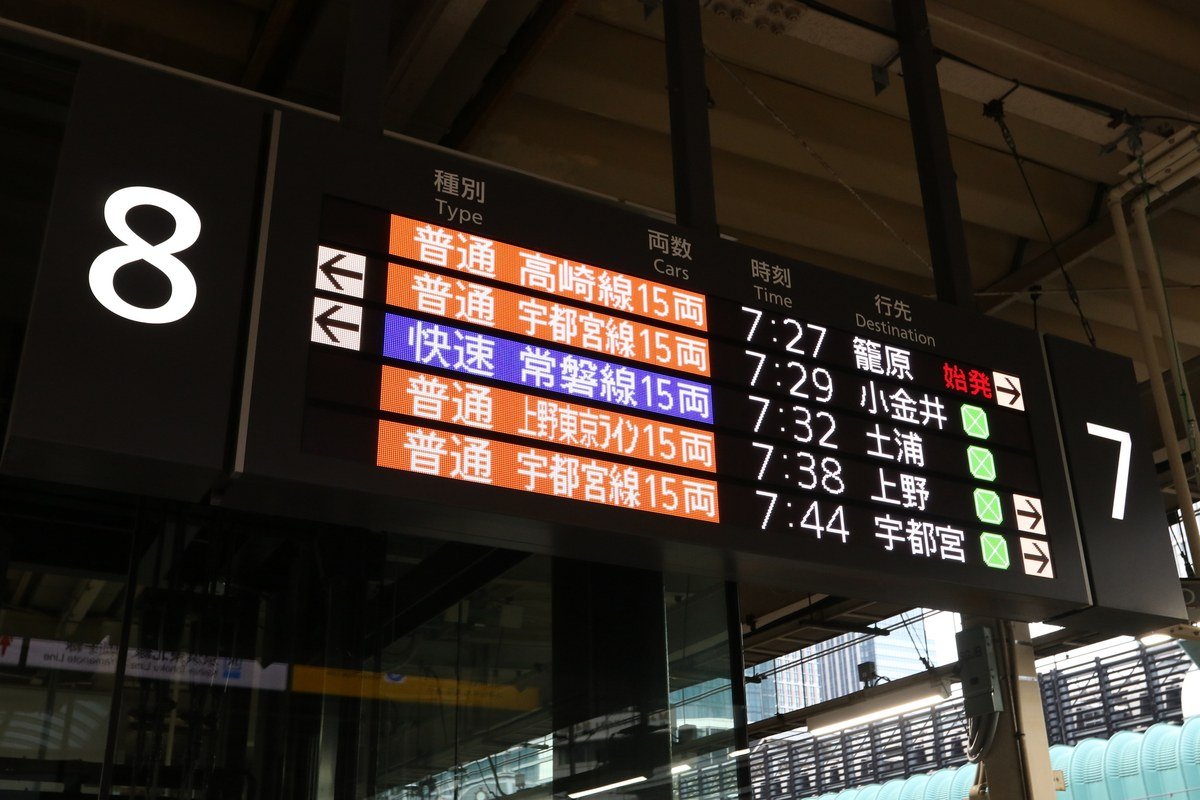 駅で電車の時刻表を確認する様子